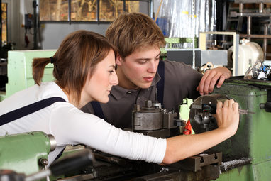 Zwei Jugendliche schauen sich eine Maschine in der Werkstatt an