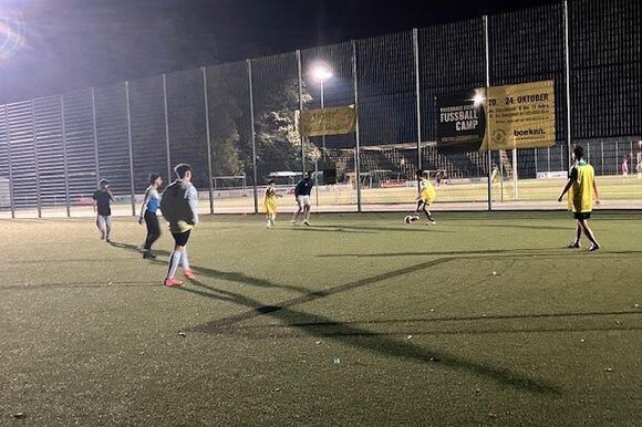 Junge Menschen spielen Fußball auf Kunstrasen