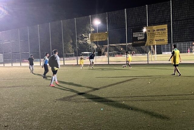 Junge Menschen spielen Fußball auf einem Kunstrasenplatz