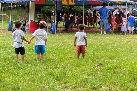 Kleine Kinder und im Hintergrund ein offenes Festzelt mit vielen Menschen
