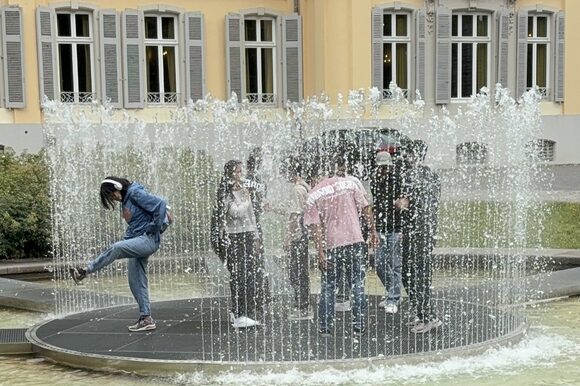 Eine Gruppe Jugendlicher steht auf der Plattform des Wasserbrunnens vor Schloss Morsbroich.