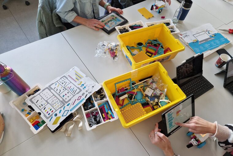 Einige Personen sitzen am Tisch und bauen mit Lego