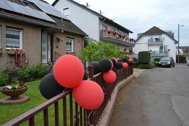 Luftballons in Bayer 04-Farben an Häusern einer Straße