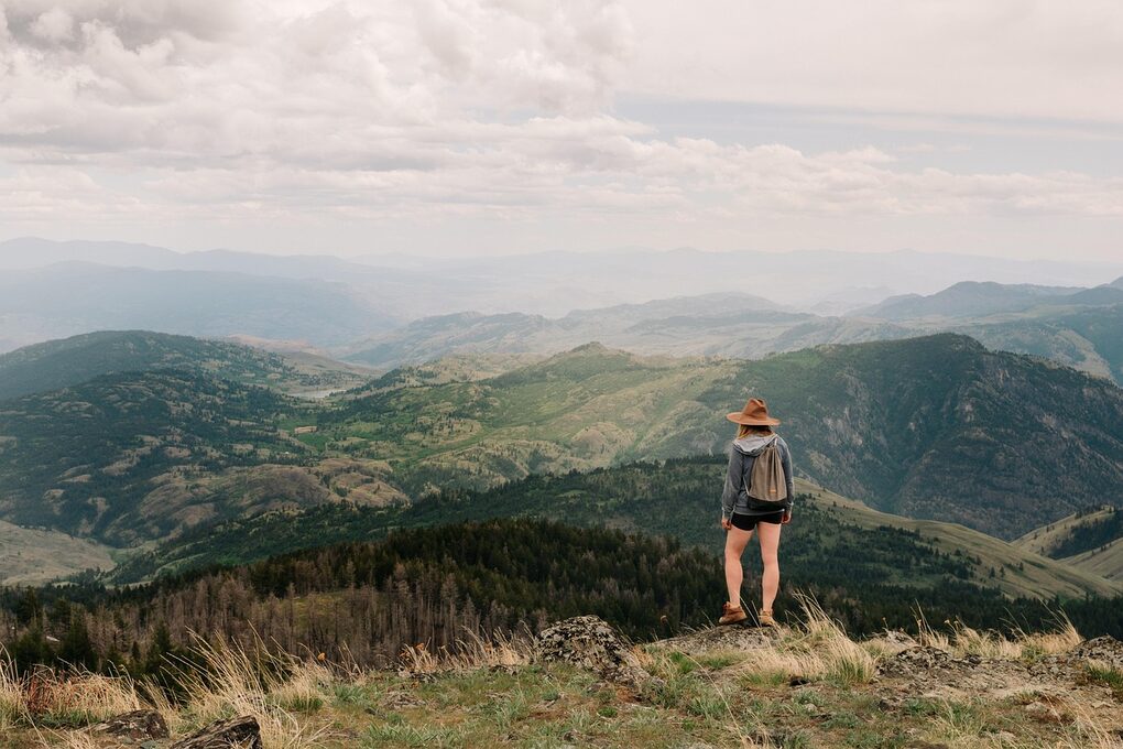 Eine Frau steht im Freien und blickt auf eine bergige Landschaft