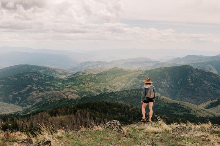 Eine Frau steht im Freien und blickt auf eine bergige Landschaft