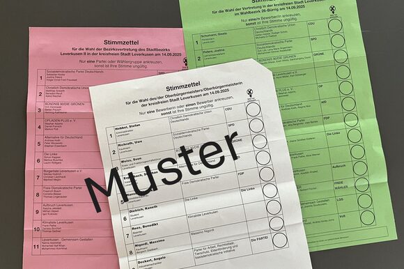Muster: die drei Stimmzettel zur Kommunalwahl 2025 in Leverkusen. Der weiße Stimmzettel ist für die Wahl des oder der Oberbürgermeister/in, der grüne für die Wahl zum Rat der Stadt und der rote für die Wahl der Bezirksvertretung