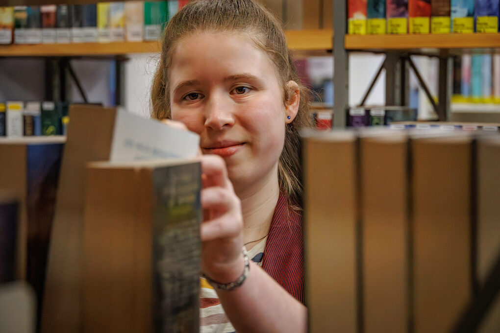 Eine Schülerin nimmt ein Buch aus dem Regal